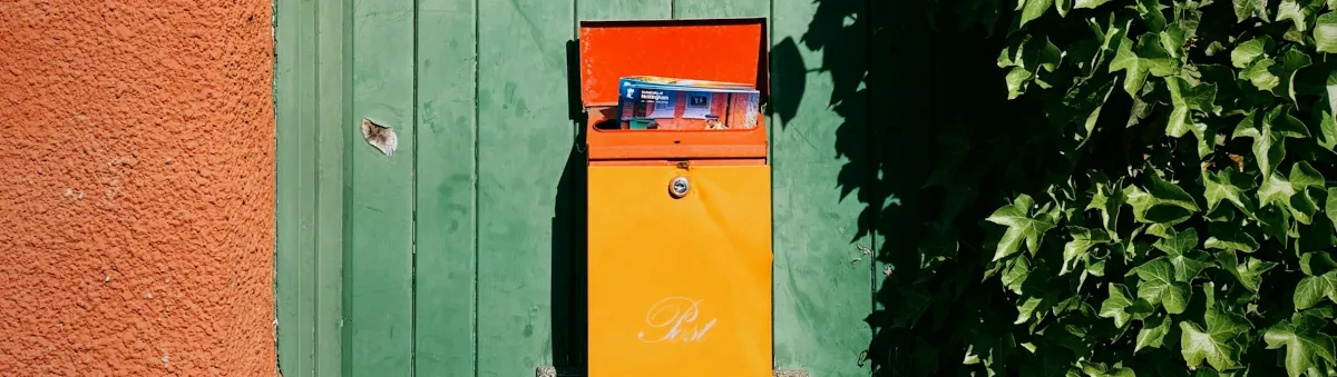Bunte Briefkästen an einer alten grünen Holztür, um mit Greenkeywelt in Kontakt zu treten
